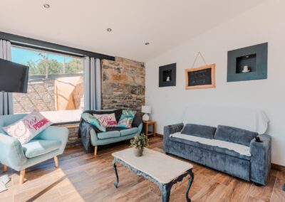 Salon lumineux avec mur en pierre apparente dans un gîte