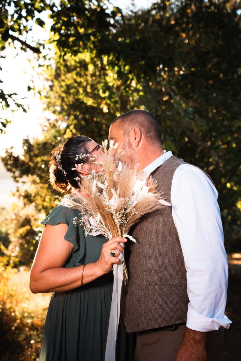 Couple de mariés qui s’embrassent sous les arbres, reportage de mariage